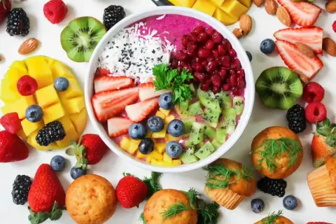 Frukostskål med bär, kiwi, mango och kokos. Muffins och mandlar runt om. En vitaminrik start på dagen!